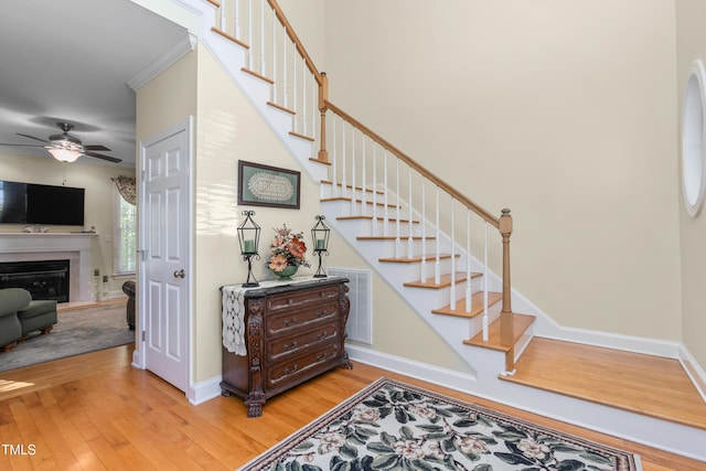 staircase with ceiling fan, ornamental molding, and hardwood / wood-style floors