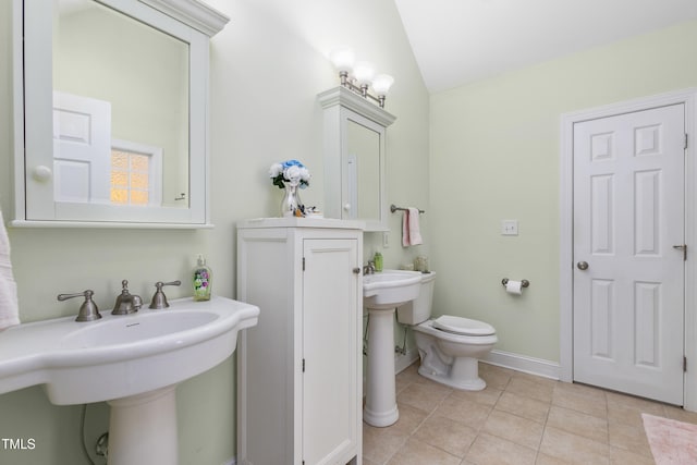 bathroom with toilet, lofted ceiling, sink, and tile patterned floors