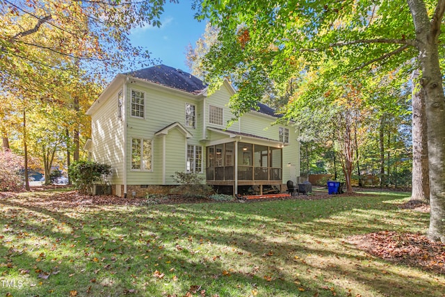 rear view of property featuring a yard and a sunroom