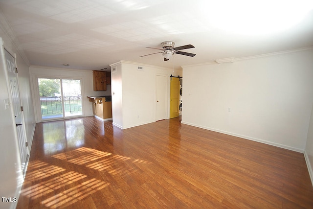 unfurnished living room with ceiling fan, a barn door, dark hardwood / wood-style floors, and crown molding