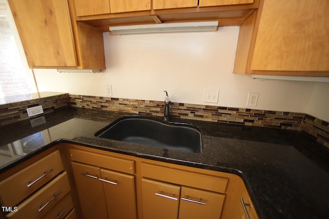 kitchen featuring dark stone countertops, tasteful backsplash, and sink