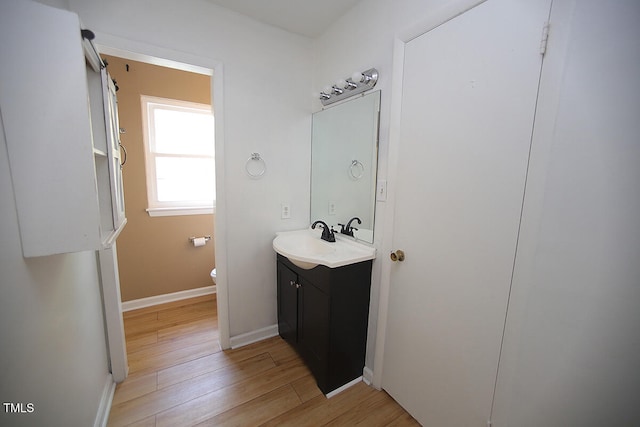 bathroom with hardwood / wood-style flooring, vanity, and toilet