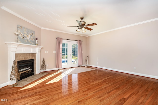 unfurnished living room featuring wood-type flooring, french doors, crown molding, a tile fireplace, and ceiling fan