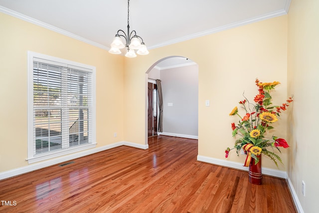 unfurnished room with hardwood / wood-style flooring, a notable chandelier, and ornamental molding