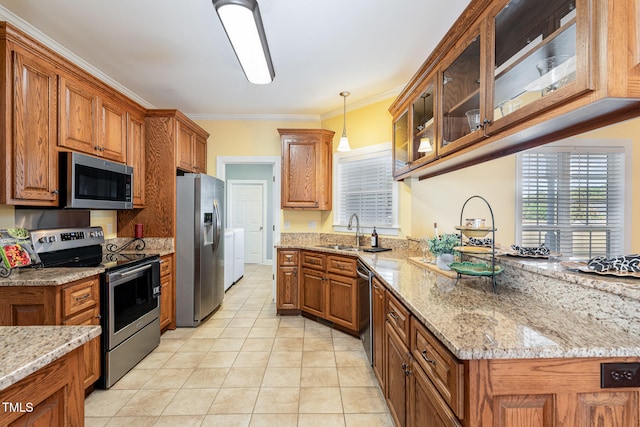 kitchen with ornamental molding, stainless steel appliances, decorative light fixtures, sink, and independent washer and dryer