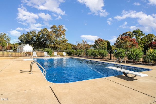 view of swimming pool with a patio and a diving board