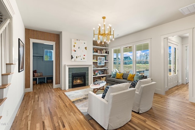 living room featuring light hardwood / wood-style floors, an inviting chandelier, and a tiled fireplace