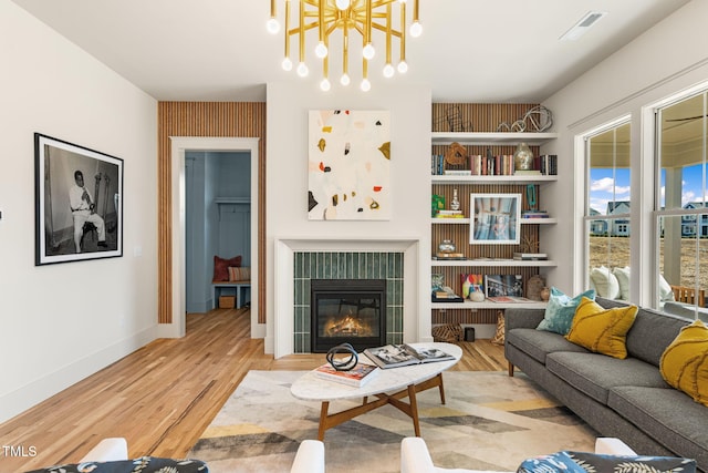 living room with light hardwood / wood-style flooring, a chandelier, and a tile fireplace