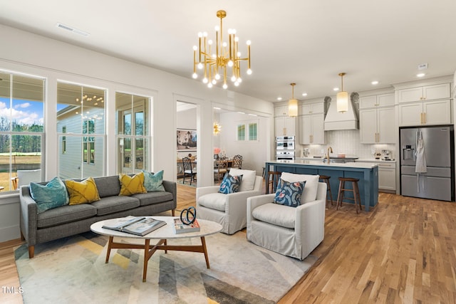 living room featuring a chandelier, sink, and light wood-type flooring