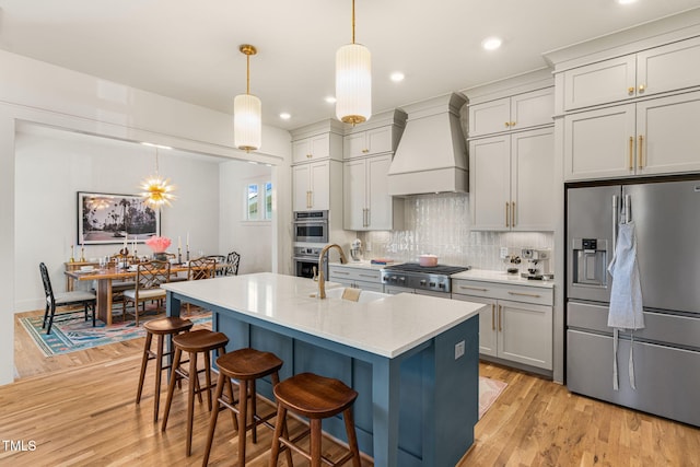 kitchen with light hardwood / wood-style flooring, sink, pendant lighting, custom exhaust hood, and appliances with stainless steel finishes