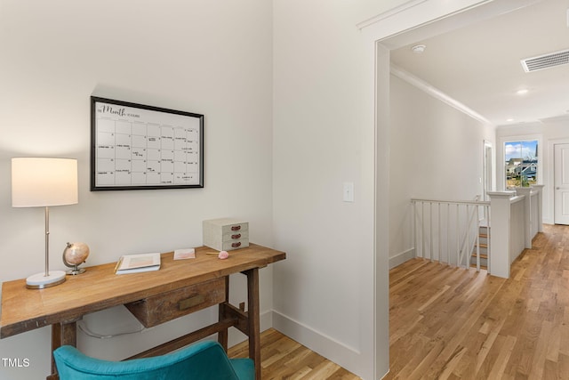 office with light hardwood / wood-style flooring and crown molding