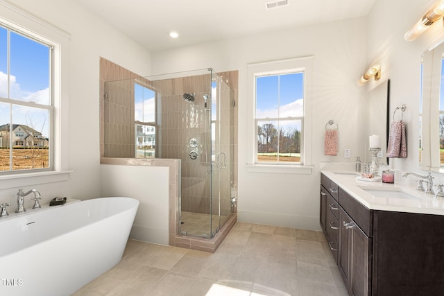 bathroom featuring vanity, independent shower and bath, a healthy amount of sunlight, and tile patterned floors