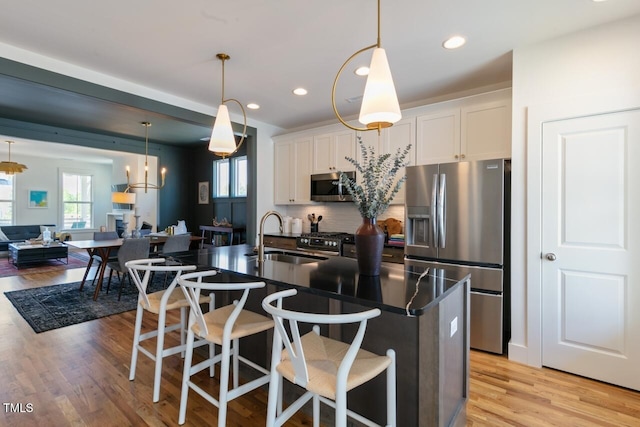 kitchen with a kitchen island with sink, appliances with stainless steel finishes, sink, and white cabinets