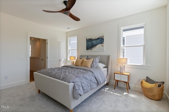 bedroom featuring a walk in closet, light carpet, multiple windows, and ceiling fan