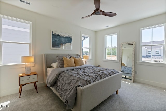 carpeted bedroom with multiple windows and ceiling fan