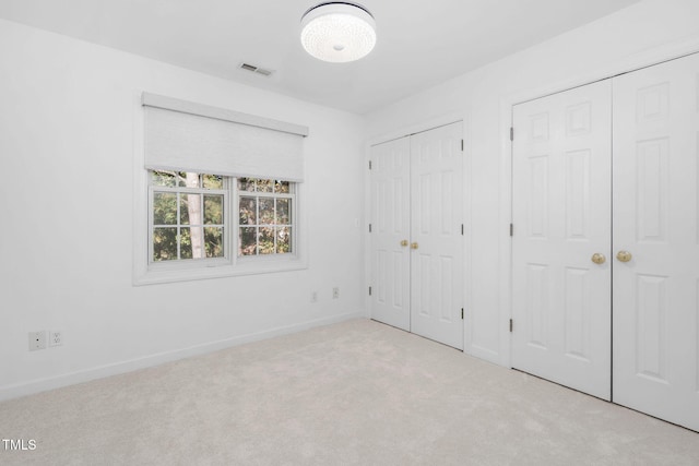 unfurnished bedroom featuring two closets, carpet flooring, and baseboards