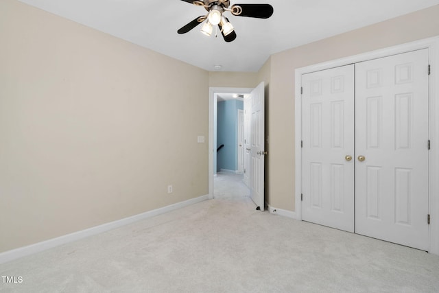 unfurnished bedroom with light colored carpet, a closet, baseboards, and a ceiling fan