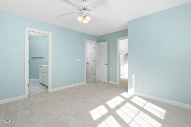 unfurnished bedroom with ceiling fan, a spacious closet, light colored carpet, connected bathroom, and a closet