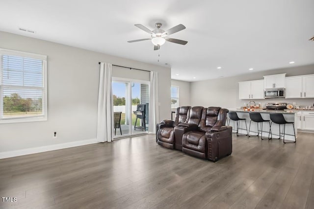 living room featuring ceiling fan and dark wood-type flooring