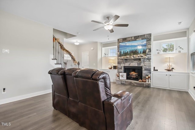 living room featuring a stone fireplace, ceiling fan, and hardwood / wood-style flooring