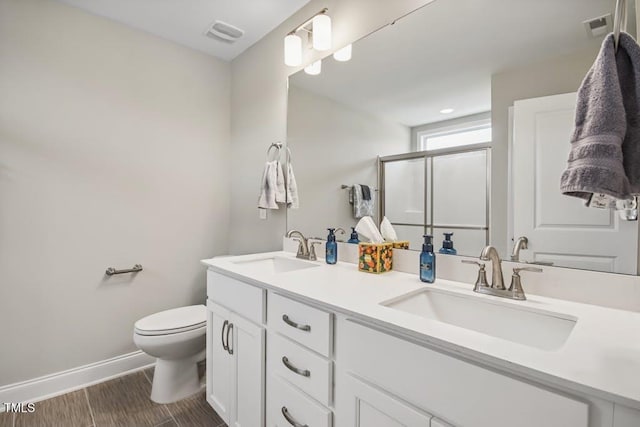 bathroom featuring hardwood / wood-style flooring, vanity, an enclosed shower, and toilet