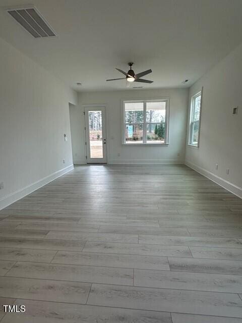 spare room with ceiling fan, plenty of natural light, and light hardwood / wood-style flooring