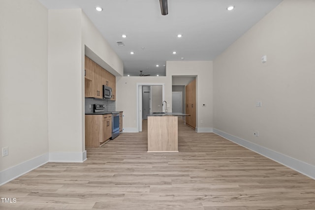 kitchen with light brown cabinetry, sink, light wood-type flooring, an island with sink, and stainless steel appliances