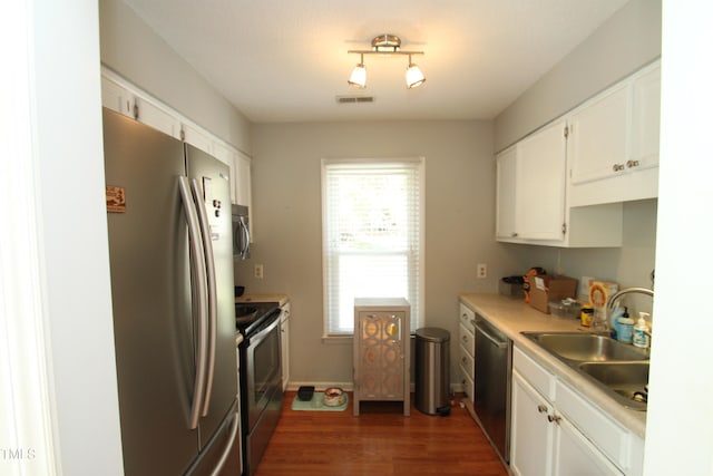 kitchen with dark wood-type flooring, appliances with stainless steel finishes, sink, and white cabinets