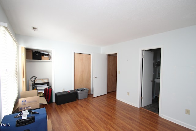 bedroom with connected bathroom and dark wood-type flooring