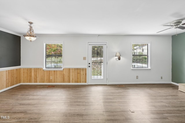 unfurnished room featuring hardwood / wood-style floors, wood walls, and a healthy amount of sunlight