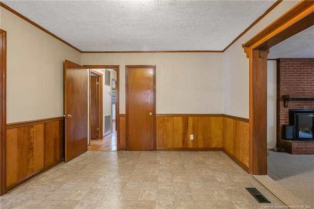 spare room with a textured ceiling, a fireplace, and wood walls