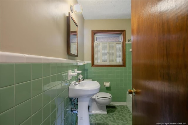 bathroom with tile walls, a textured ceiling, toilet, and tile patterned floors