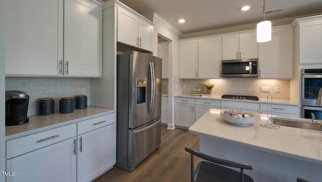 kitchen with white cabinetry, stainless steel appliances, pendant lighting, and dark hardwood / wood-style floors