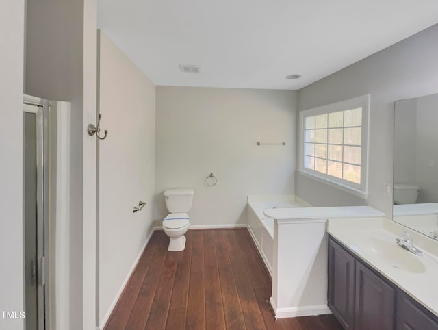 bathroom with toilet, hardwood / wood-style floors, vanity, and a bath