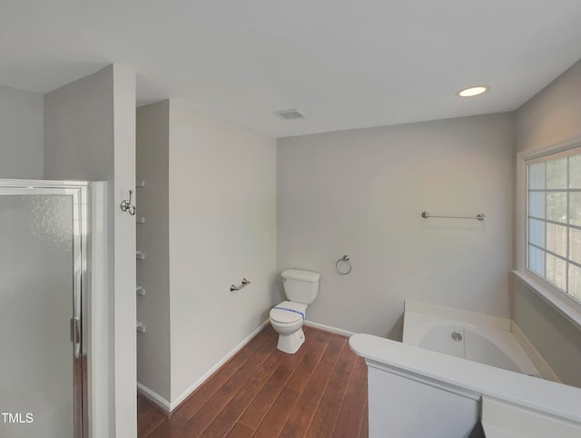 bathroom with toilet, hardwood / wood-style floors, and plus walk in shower