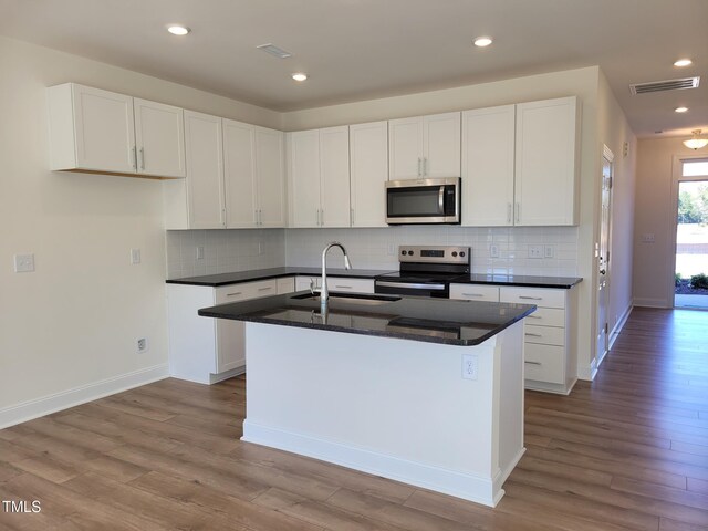 3616 Tarmac Rd Unit Ep 129, Wilson, NC 27896 - kitchen featuring stainless steel appliances, a sink, wood finished floors, an island with sink, and white cabinetry