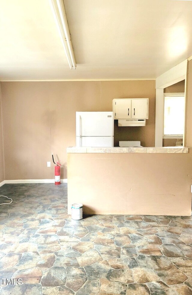 325 Ranch Farm Rd Unit A B, Raleigh, NC 27603 - kitchen featuring freestanding refrigerator, stone flooring, under cabinet range hood, and white cabinetry