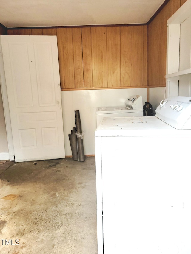 laundry area with washing machine and dryer, cabinets, and wooden walls