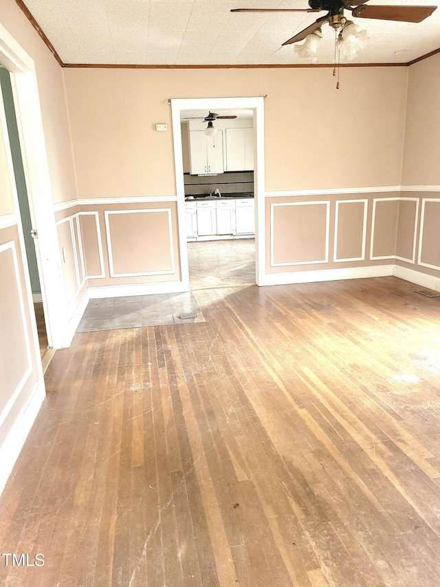 empty room featuring ornamental molding, light wood-type flooring, sink, and ceiling fan