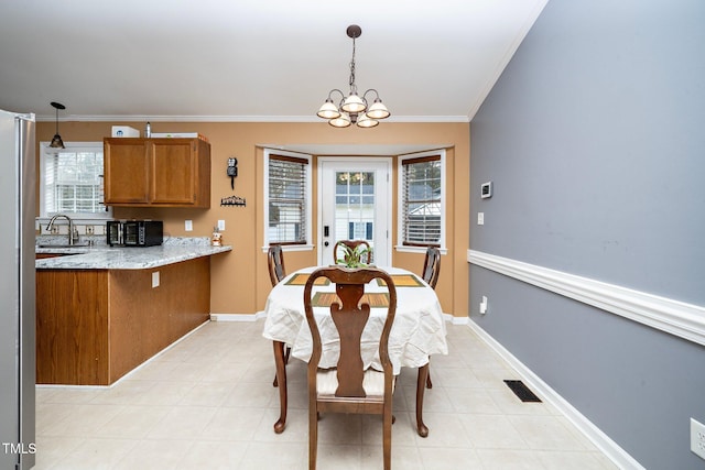 dining space with crown molding, a chandelier, sink, and a wealth of natural light