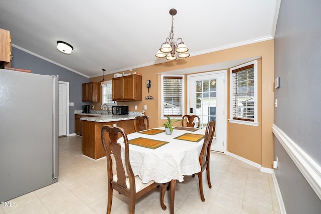 dining space featuring crown molding, lofted ceiling, sink, and a notable chandelier