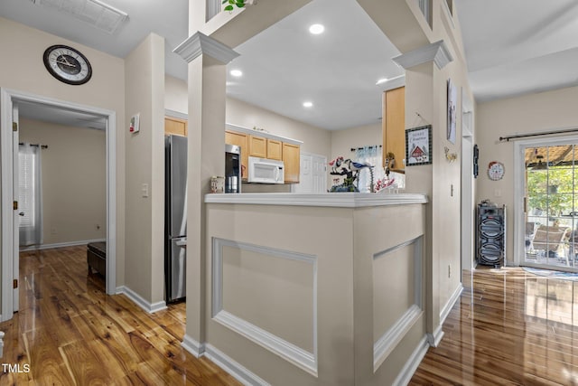 kitchen with hardwood / wood-style floors, light brown cabinetry, ornate columns, and stainless steel refrigerator