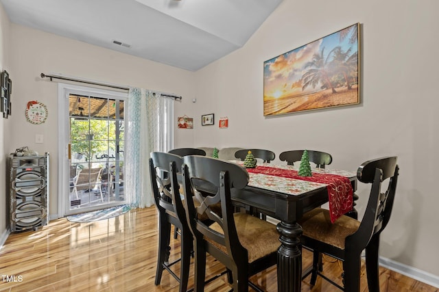 dining room with wood-type flooring and vaulted ceiling