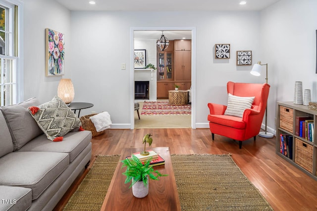 living room featuring a large fireplace, an inviting chandelier, and hardwood / wood-style floors