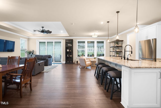 kitchen featuring stainless steel fridge, white cabinets, decorative light fixtures, and a healthy amount of sunlight