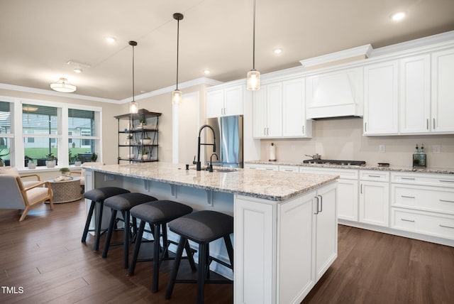 kitchen with a center island with sink, stainless steel fridge, and white cabinets