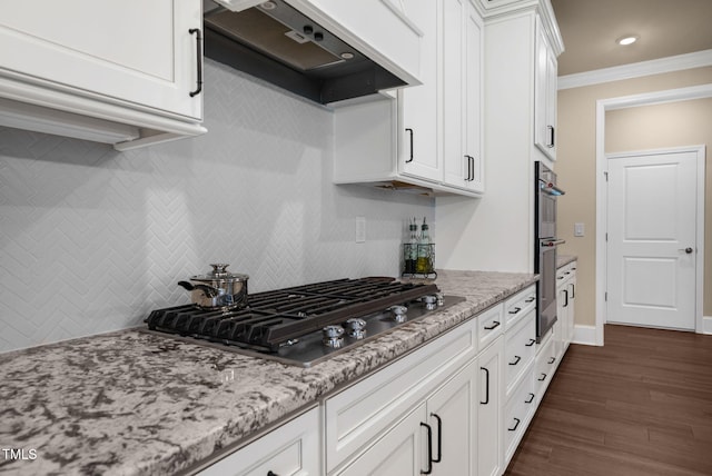 kitchen featuring white cabinets, appliances with stainless steel finishes, dark hardwood / wood-style floors, crown molding, and ventilation hood