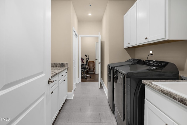 washroom with light tile patterned flooring, independent washer and dryer, and cabinets