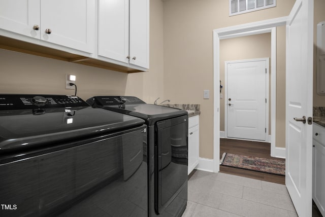 washroom featuring light hardwood / wood-style floors, washer and dryer, and cabinets