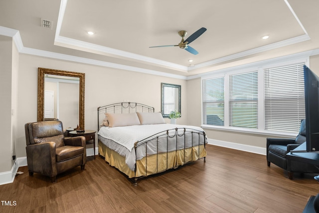 bedroom featuring ornamental molding, hardwood / wood-style flooring, a tray ceiling, and ceiling fan